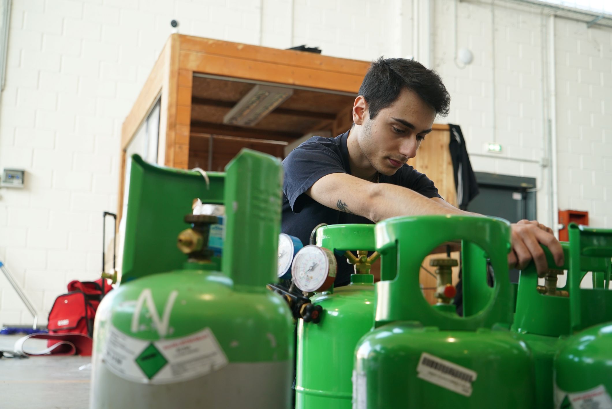 Tecnico A.M. al lavoro su bombole di gas refrigerante in officina
